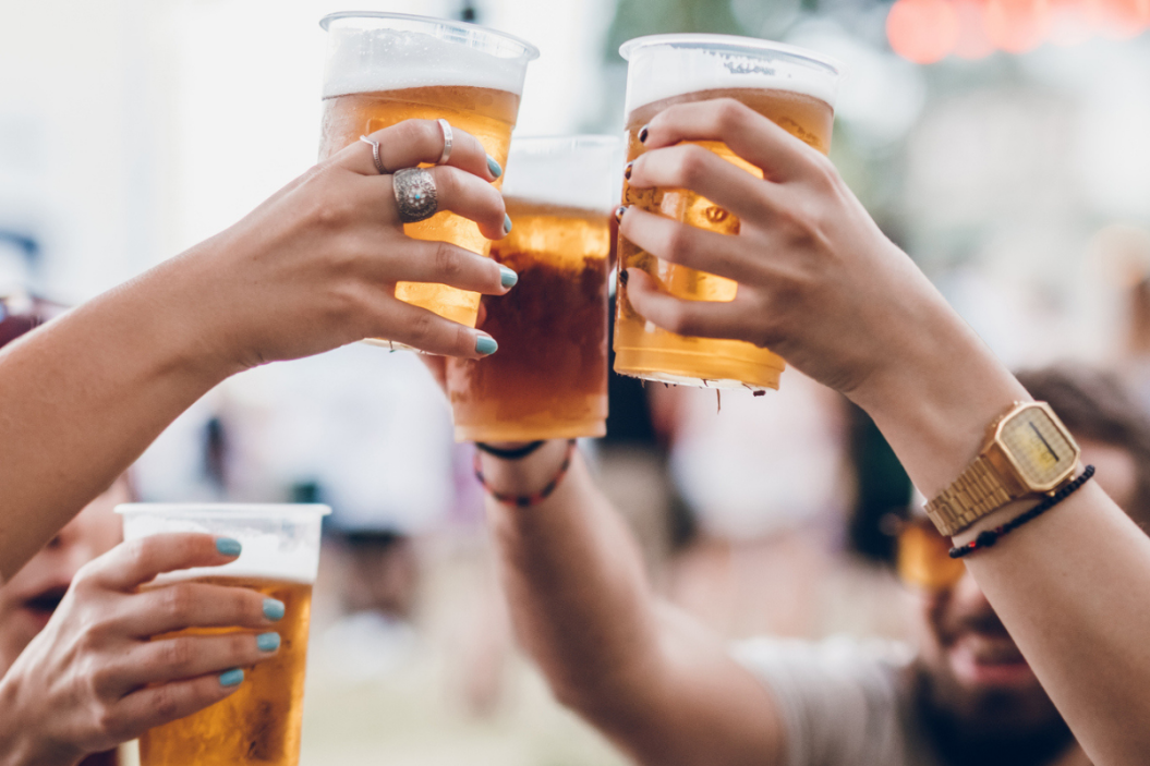 Group of four friends toasting with beer on a music festival