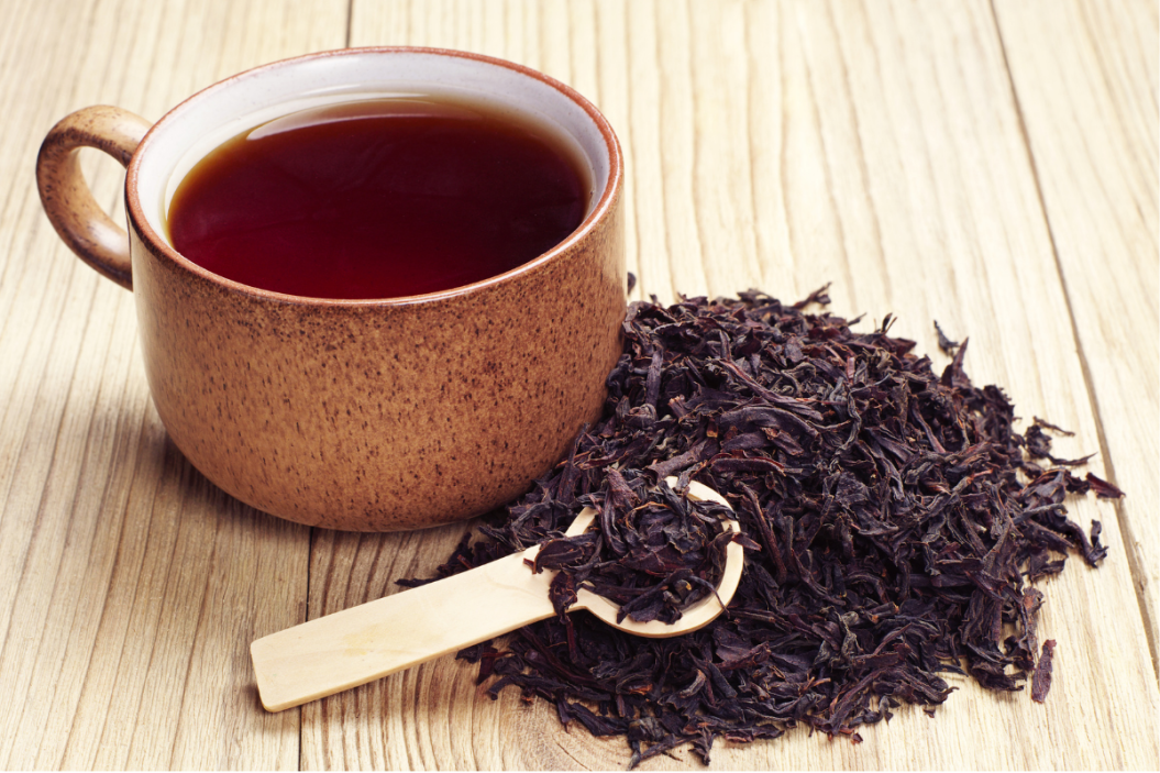 Black tea in a cup and dried leaves on wooden backgroundd tea